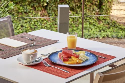 a table with a plate of food and a glass of orange juice at URH - Hotel Molí del Mig in Torroella de Montgrí