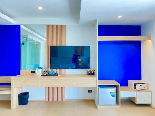 a room with a desk with a tv and blue walls at Armoni Patong Beach Hotel in Patong Beach