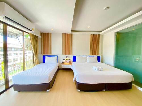 a bedroom with two beds and a window at Armoni Patong Beach Hotel in Patong Beach