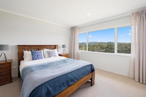 a bedroom with a bed and a large window at A million city views in Rotorua