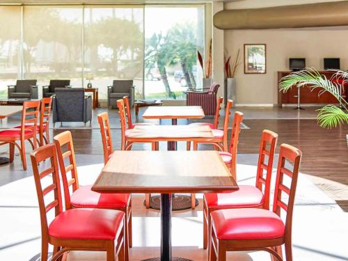 a restaurant with wooden tables and red chairs at Ibis Monterrey Aeropuerto in Monterrey