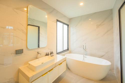 een badkamer met een bad, een wastafel en een spiegel bij HighView PoolVilla at Khaoyai in Ban Bung Toei
