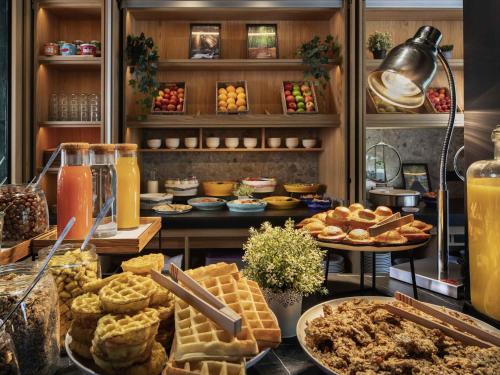 een buffet met wafels en andere gerechten op tafel bij Novotel Suites Paris CDG Airport Villepinte in Roissy-en-France
