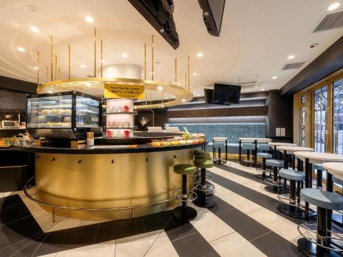 a restaurant with a gold counter and stools at KOKO HOTEL Osaka Umeda in Osaka