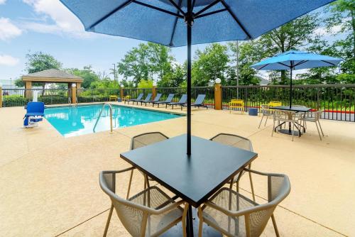 a table and chairs with umbrellas next to a pool at Hampton Inn Foley in Foley