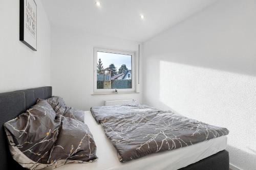 een bed in een witte kamer met een raam bij Hivent Ferienwohnungen in Bad Dürrheim