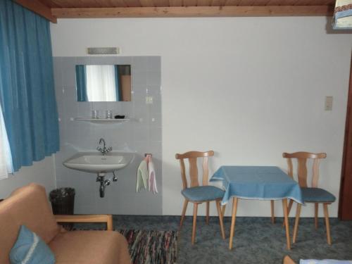 uma casa de banho com um lavatório, uma mesa e cadeiras em Haus Pranger em Gschnitz