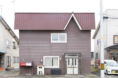 een bruin huis met een rood dak op een straat bij Niseko Homey Home in Kutchan
