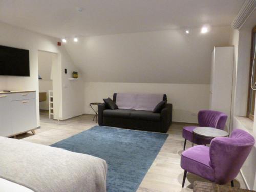 a living room with a couch and purple chairs at B&B 't Hof van Spiere in Spiere