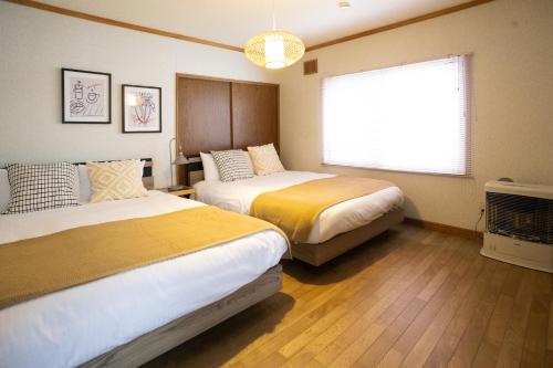 een hotelkamer met twee bedden en een raam bij Niseko Homey Home in Kutchan