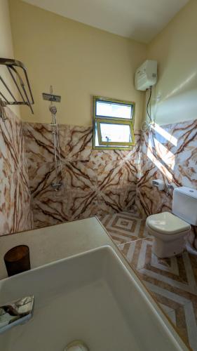 a bathroom with a bath tub and a toilet at Joujo's Jungle Guest House in Nungwi