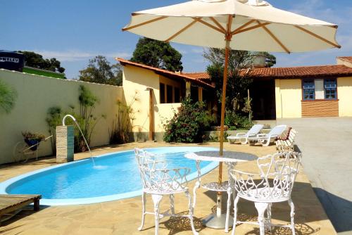 a table with an umbrella next to a pool at Pousada Luz do Sol in Carrancas