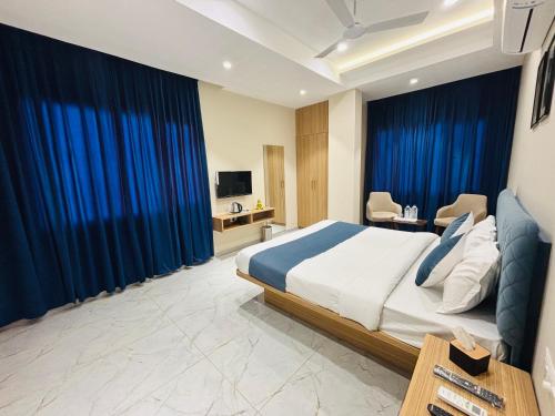 a bedroom with a large bed with blue curtains at MG Plaza Hotel in Jodhpur