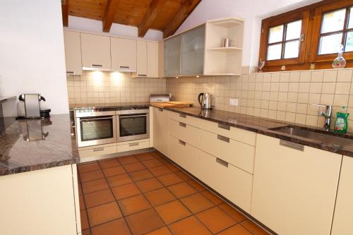 a kitchen with white cabinets and an orange tile floor at Chalet Huwi Zermatt in Zermatt