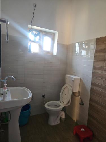 a bathroom with a toilet and a sink and a window at Jaibari Basa in Ukhimath