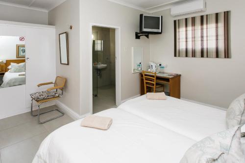 a white bedroom with a bed and a desk at Wagon Wheel Country Lodge in Beaufort West