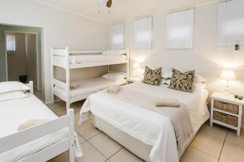 two beds in a white room with two bunk beds at Wagon Wheel Country Lodge in Beaufort West