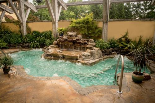 a swimming pool with a waterfall in a garden at Mirbeau Inn & Spa - Skaneateles in Skaneateles