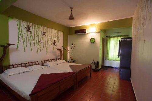 a bedroom with a large bed with white sheets at Tapovan Fruitopia in Sultan Bathery