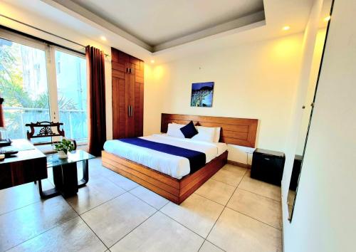 a bedroom with a bed and a desk and a window at Stays - NH 8 in Gurgaon