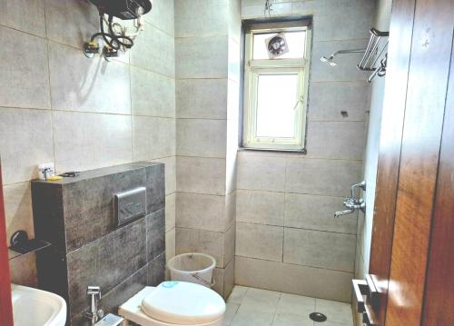 a bathroom with a toilet and a sink and a window at Stays - NH 8 in Gurgaon