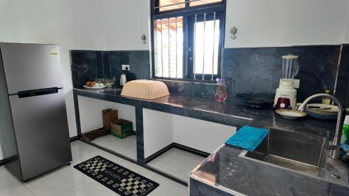 una cucina con un bancone con un lavello e un frigorifero di Nomad's Peak Hiriketiya a Dikwella