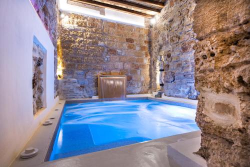 an indoor pool in a brick walled room with a blue swimming pool at Boutique Hotel Porta di Castro in Palermo