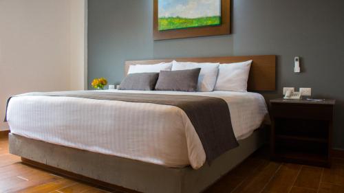 1 dormitorio con 1 cama grande con colcha blanca en Eco Hotel Guadalajara Expo, en Guadalajara