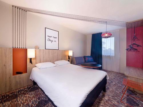 een hotelkamer met een groot bed en een stoel bij ibis Styles Toulouse Lavaur in Lavaur