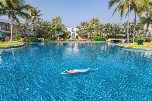 a woman swimming in a swimming pool at a resort at Sheraton Hua Hin Resort & Spa in Cha Am