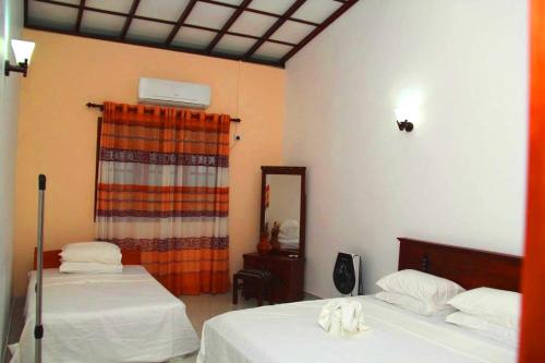 a room with two beds and a mirror at Bentota Backpackers Bay Hostel in Bentota