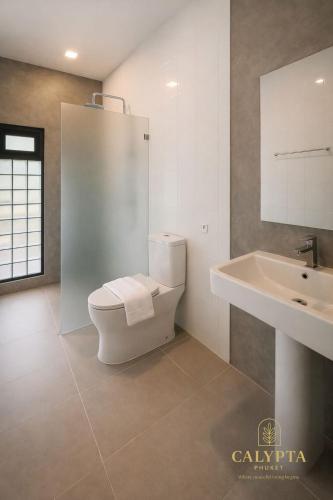 een witte badkamer met een toilet en een wastafel bij Calypta Resort Phuket in Phuket