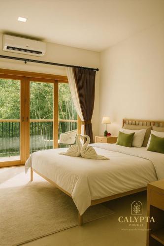 een slaapkamer met twee bedden en een groot raam bij Calypta Resort Phuket in Phuket