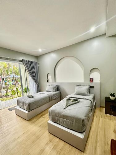 a bedroom with two beds and a large window at New Mekar Jaya Hotel in Legian