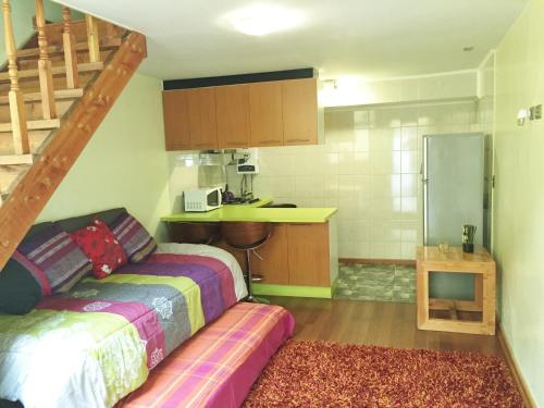 a small kitchen with a bed and a refrigerator at Tribu Malen Apartamentos in Temuco
