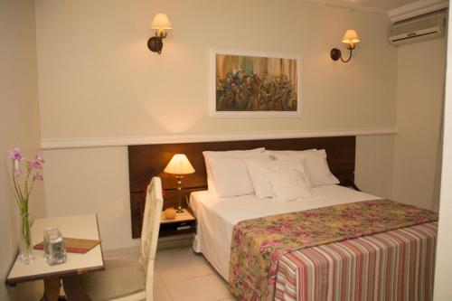 pokój hotelowy z łóżkiem i stołem oraz łóżkiem o wymiarach sześciu w obiekcie Mariano Palace Hotel w mieście Campinas