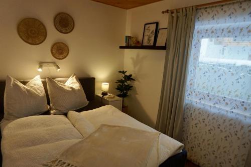 a bedroom with a bed with white sheets and a window at Bergnest Fieberbrunn in Fieberbrunn