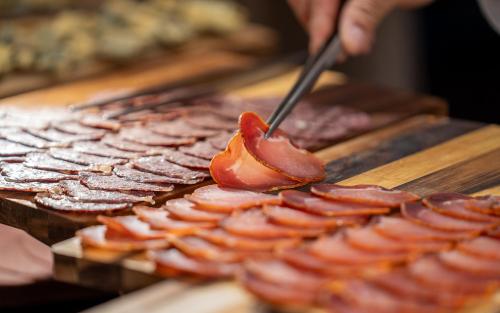 Iemand snijdt spek op een grill. bij Hotel Montarto in Baqueira-Beret