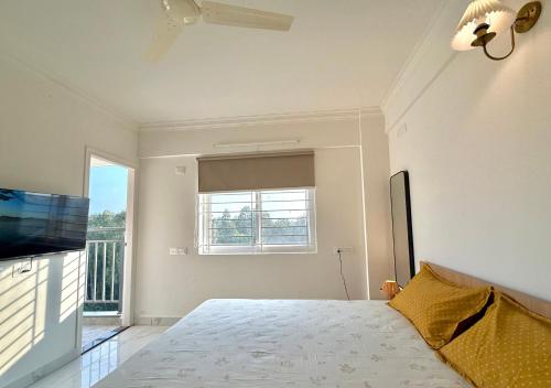 une chambre blanche avec un lit et une télévision dans l'établissement HomeSlice Sarjapur - Balcony Rooms, à Bangalore