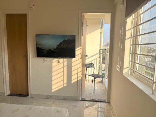 Cette chambre dispose d'une porte menant à un balcon avec une télévision. dans l'établissement HomeSlice Sarjapur - Balcony Rooms, à Bangalore