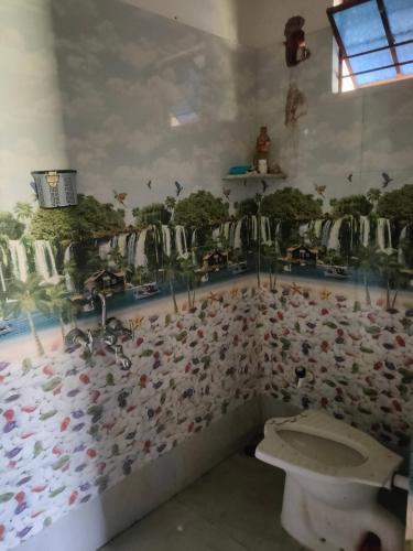 a bathroom with a toilet and a wall covered in animals at Laxmi Narasimha homestay in mayapur