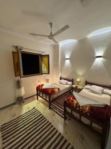 a bedroom with two beds and a flat screen tv at MERIT Guest House in Aswan
