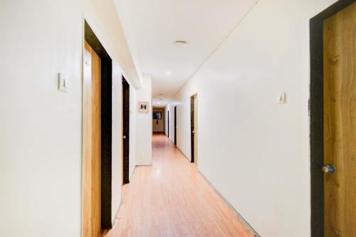 un couloir vide avec des murs blancs et du parquet dans l'établissement FabHotel White Ridge Chaitanyapuri, à Hyderabad