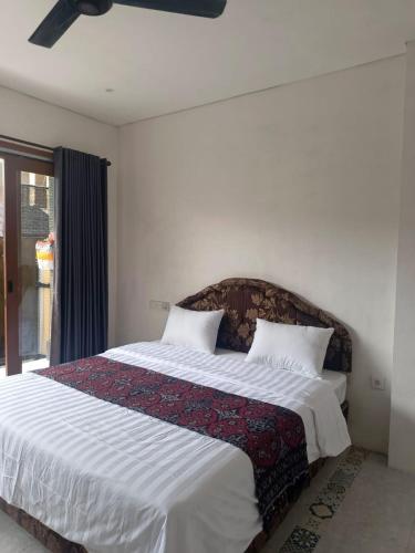 a bedroom with a large bed with white sheets and pillows at Rumah Ramah Ubud in Ubud