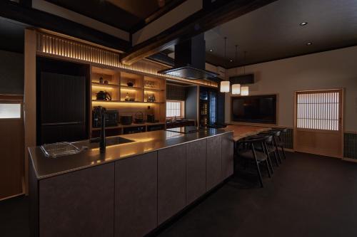 a kitchen with a counter and a bar with stools at えにし美山 霞月 -kagetsu- in Nantan city