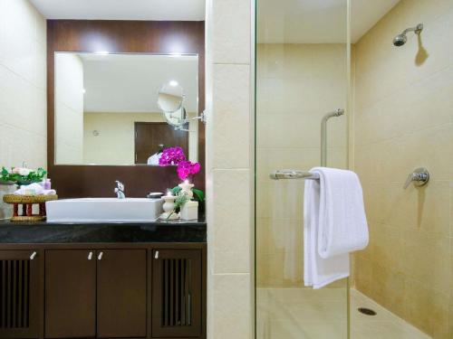 een badkamer met wastafel en douche met spiegel bij Grand Mercure Bangkok Asoke Residence in Bangkok