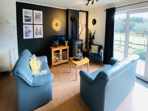 een woonkamer met twee blauwe stoelen en een televisie bij Family Home in Sourbrodt in Sourbrodt