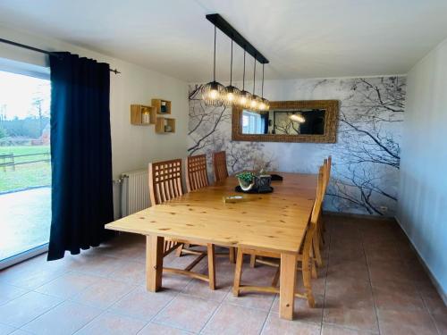 een houten eettafel met stoelen en een spiegel bij Family Home in Sourbrodt in Sourbrodt