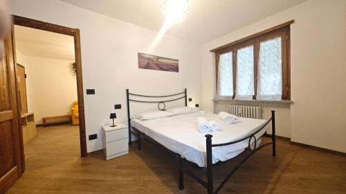 ein Schlafzimmer mit einem Bett mit weißer Bettwäsche und einem Fenster in der Unterkunft Hostdomus - Chez Paul in Cesana Torinese
