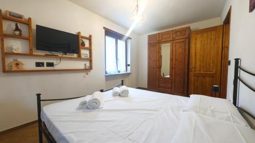 Schlafzimmer mit einem weißen Bett und einem TV an der Wand in der Unterkunft Hostdomus - Chez Paul in Cesana Torinese